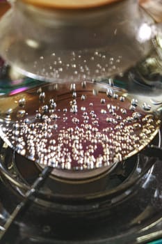 A detailed closeup of water actively boiling on a stove, revealing beautiful bubbles and reflections shimmering