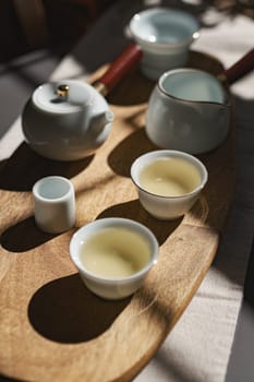 A serene and inviting tea setup that features a delicate white teapot along with cups placed on a wooden tray