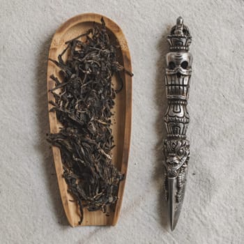 An artistic and creative arrangement of dried tea leaves along with a decorative tool designed for tea preparation