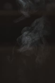 An abstract image showcases ethereal smoke patterns gracefully flowing against a dark and mysterious backdrop