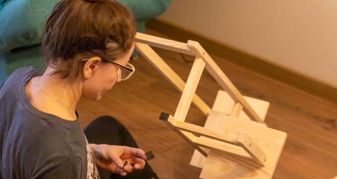 Woman is assembling wooden shelf
