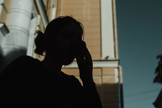 A shadowy figure, lost in deep contemplation and thought, stands against a striking and vibrant urban backdrop