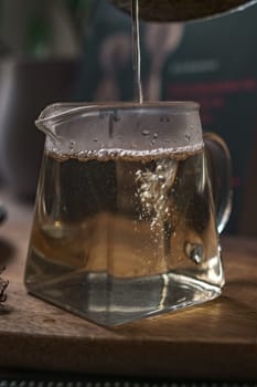 A captivating closeup of aromatic tea being elegantly poured into a stylish geometric teapot, showcasing bubbles