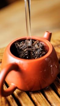 A tranquil and serene moment of tea brewing, with hot water slowly being poured into a beautiful clay teapot