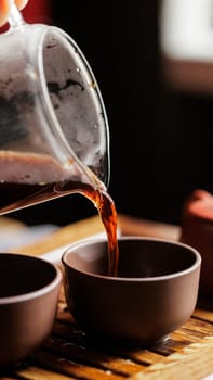 A serene moment of pouring fragrant tea into beautifully designed cups, perfect for relaxation and enjoyment