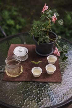 Take a moment to relish a peaceful tea experience with beautiful, delicate cups alongside a vibrant blooming plant