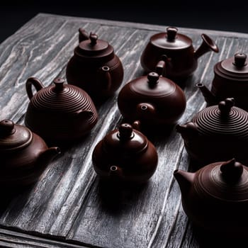 A striking and colorful display of various traditional teapots arranged on a beautifully textured wooden surface