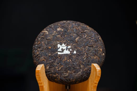 A beautifully crafted round compressed tea cake is on display, showcasing its unique texture and artistry