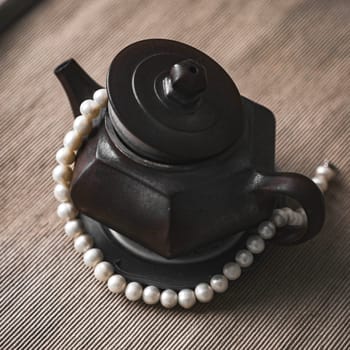 A stylish black teapot adorned with pearls, showcasing exceptional craftsmanship and stunning detail