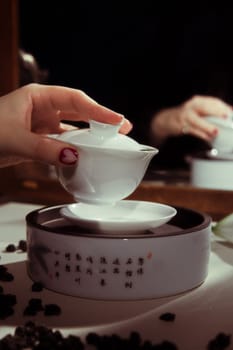 A serene tea ceremony that beautifully displays a hand pouring tea from exquisitely crafted porcelain pieces