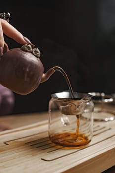 A beautifully crafted teapot pouring tea into a glass pitcher, highlighting a serene tea experience.