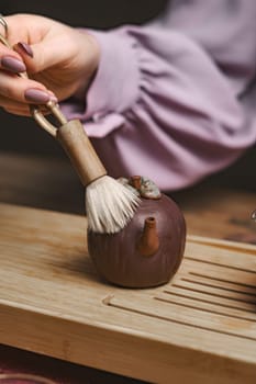 A whimsical chocolate teapot is delicately styled with an artistic brush placed on a lovely wooden surface