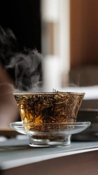 A tranquil glass of steaming herbal tea that showcases fresh leaves with an aura of elegance and refinement