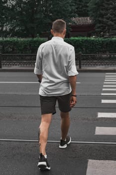 A man strolls across a busy street, showcasing a mix of urban fashion and an active outdoor lifestyle