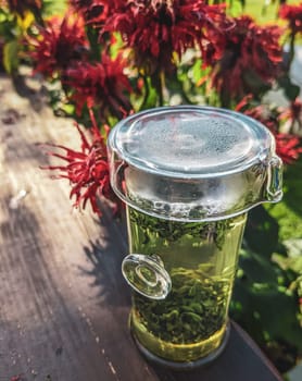 A refreshing glass of aromatic herbal tea infused with fresh herbs amid colorful blooming flowers in a sunlit garden
