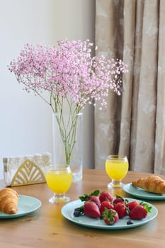 A beautifully arranged breakfast table showcasing vibrant flowers, fresh fruit, and delightful pastries