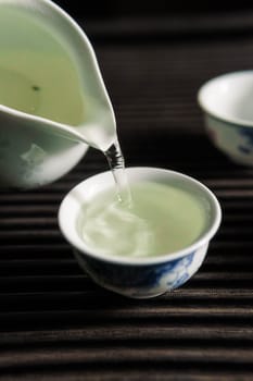 A serene moment unfolds as tea is poured into delicate porcelain cups, showcasing rich Chinese tea culture