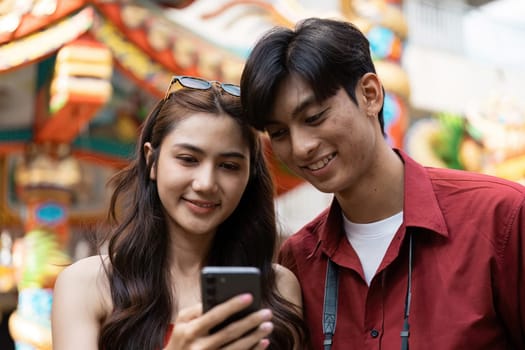 A young couple captures joyful moments during Chinese New Year celebrations in a vibrant street setting.