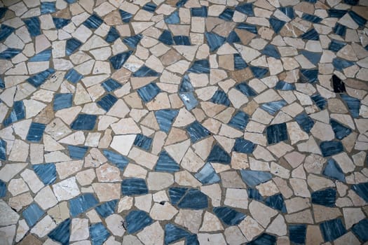 Cremona, Italy - November 27th 2024 Close-up of a decorative pavement made with irregular beige and blue marble stones forming a geometric pattern in cremona, italy