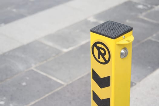 Yellow No Parking Post With Arrows On Paved Urban Street.