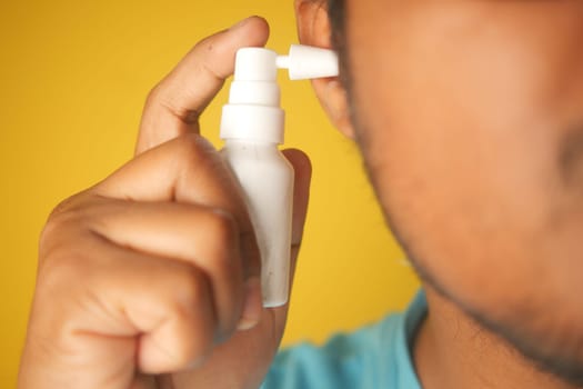 Close up of men using spray to remove earwax.