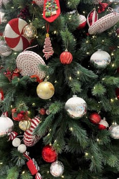Festive Christmas Tree with Ornaments.The image shows a beautifully decorated Christmas tree adorned with a variety of ornaments. The tree is lush with green branches and is illuminated by small white lights.