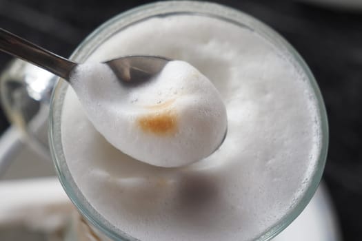A delicious cup of coffee topped perfectly with rich, creamy foam served in a glass