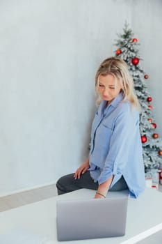 Business woman with laptop online at the christmas tree