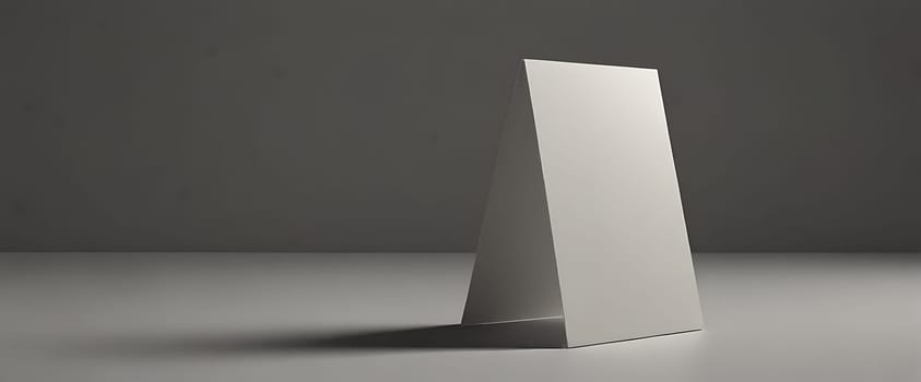 A blank white card leaning against a solid surface in a dimly lit room with a dark background.
