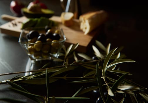 A rustic kitchen scene featuring olives, bread, and fresh produce, ideal for a gourmet culinary setting or food preparation context, evoking a warm and inviting atmosphere.