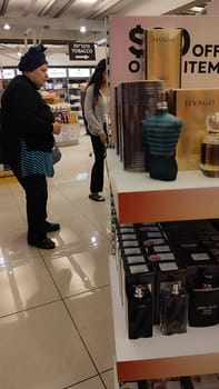 15 October 2024 Tel-Aviv Israel Ben Gurion airport, dollars items at duty free, perfume in packaging, women in perfumery market. High quality photo