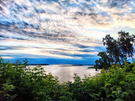 A tranquil view of a river at twilight, framed by lush greenery and colorful clouds in the sky, creating a serene atmosphere.