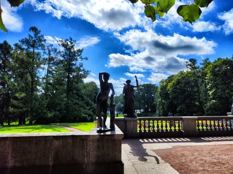The park features tall trees and vibrant green grass, creating a tranquil atmosphere on a sunny summer day