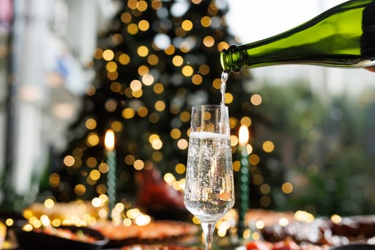Festive scene with glasses filled with sparkling wine against the background of a beautifully decorated Christmas tree. Warm atmosphere of home Christmas