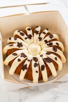 Packaging the freshly baked pumpkin bundt cake into a white paper box for gifting.