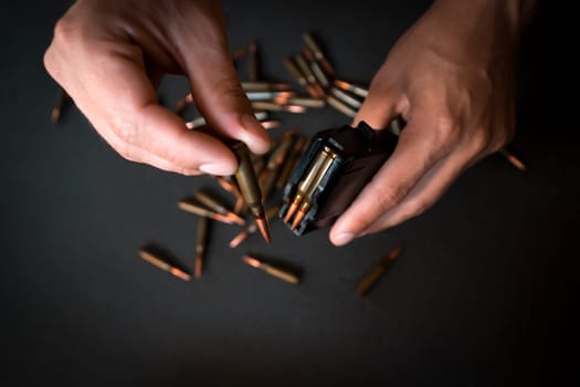 A man loads a magazine from an Ak-74 assault rifle with 5.45 caliber cartridges, a soldier cleans his weapons and ammunition, prepares a Kalashnikov assault rifle, view from above on his hands.