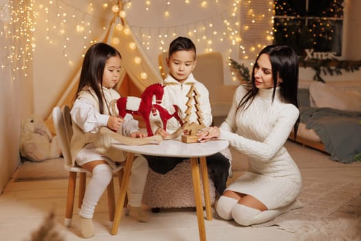 happy family, mother and children decorating christmas cookies in cozy room. christmas family evening,