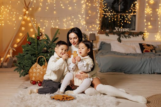 happy family, mother and children decorating christmas cookies in cozy room. christmas family evening,