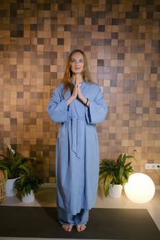 Girl in blue kimano practicing kundalini or qigong yoga in fitness gym . Spiritual energy, life force located at the base of the spine.