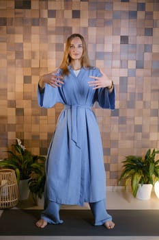 Girl in blue kimano practicing kundalini or qigong yoga in fitness gym . Spiritual energy, life force located at the base of the spine.