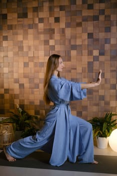Girl in blue kimano practicing kundalini or qigong yoga in fitness gym . Spiritual energy, life force located at the base of the spine.