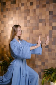 Girl in blue kimano practicing kundalini or qigong yoga in fitness gym . Spiritual energy, life force located at the base of the spine.