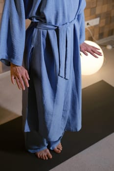 Girl in blue kimano practicing kundalini or qigong yoga in fitness gym . Spiritual energy, life force located at the base of the spine.