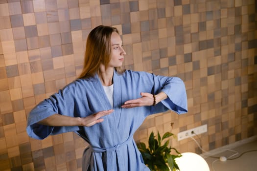 Girl in blue kimano practicing kundalini or qigong yoga in fitness gym . Spiritual energy, life force located at the base of the spine.