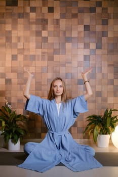 Girl in blue kimano practicing kundalini or qigong yoga in fitness gym . Spiritual energy, life force located at the base of the spine.