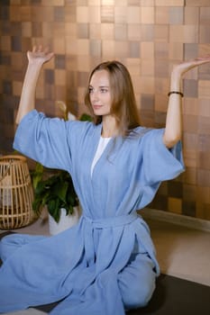 Girl in blue kimano practicing kundalini or qigong yoga in fitness gym . Spiritual energy, life force located at the base of the spine.