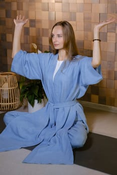Girl in blue kimano practicing kundalini or qigong yoga in fitness gym . Spiritual energy, life force located at the base of the spine.