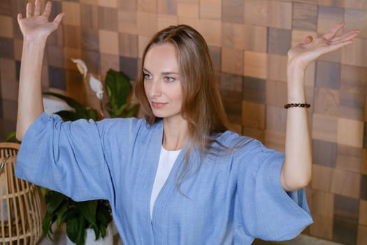 Yoga instructor in blue kimano at fitness gym . The girl does qigong yoga. The exercises are based on the movement of internal energy, the system of channels, energy centers, chakras.