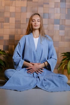 Girl in blue kimano practicing kundalini or qigong yoga in fitness gym . Spiritual energy, life force located at the base of the spine.