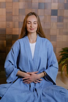 Yoga instructor in blue kimano at fitness gym . The girl does qigong yoga. The exercises are based on the movement of internal energy, the system of channels, energy centers, chakras.